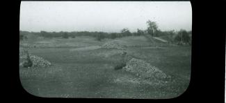 A wide angle view of piles of rocks, grass, and trees