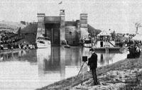 A man standing on the shore of a canal with a camera taking a photograph of lift locks